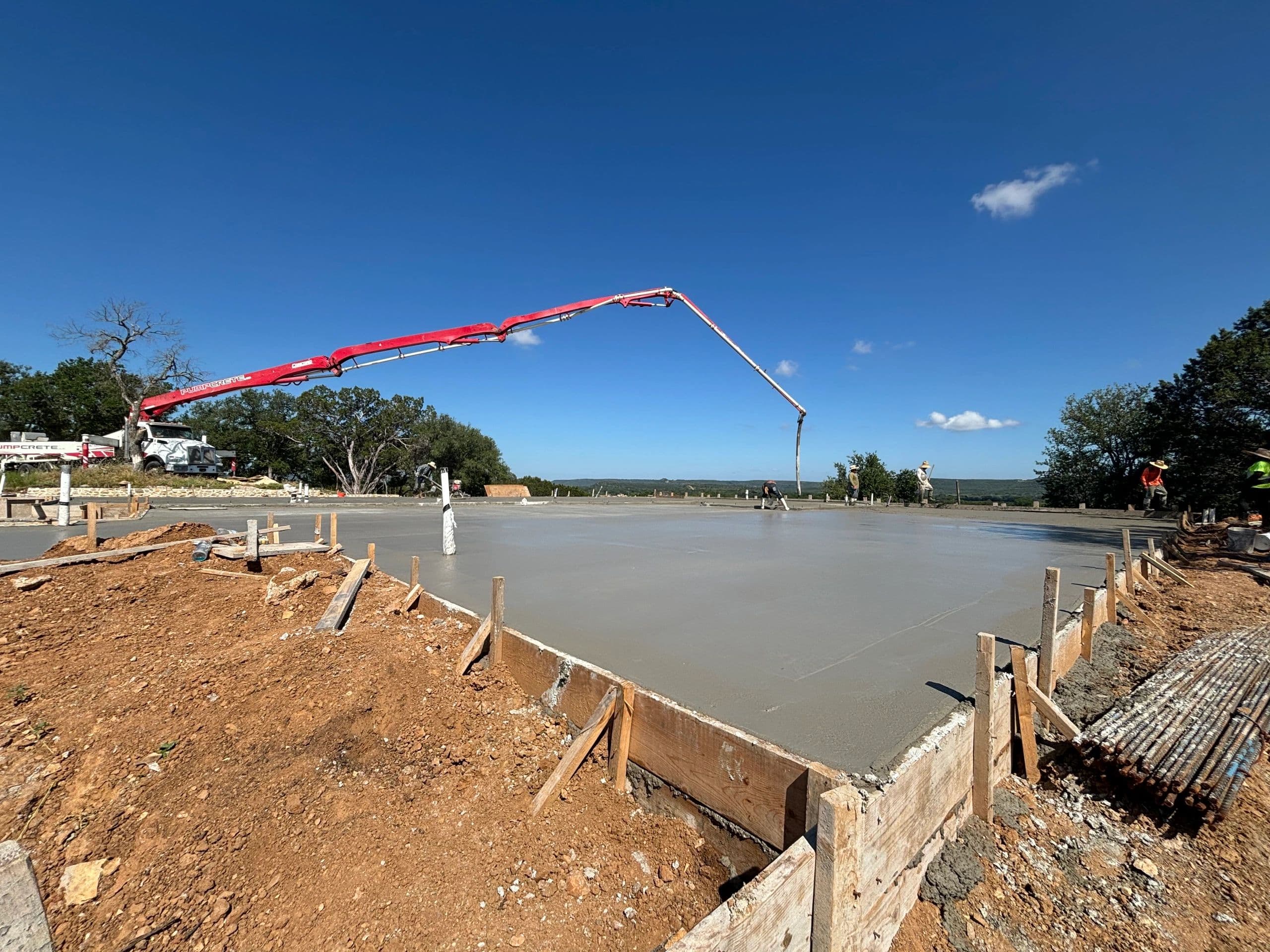 Large concrete slab pour with pump truck under blue Texas sky