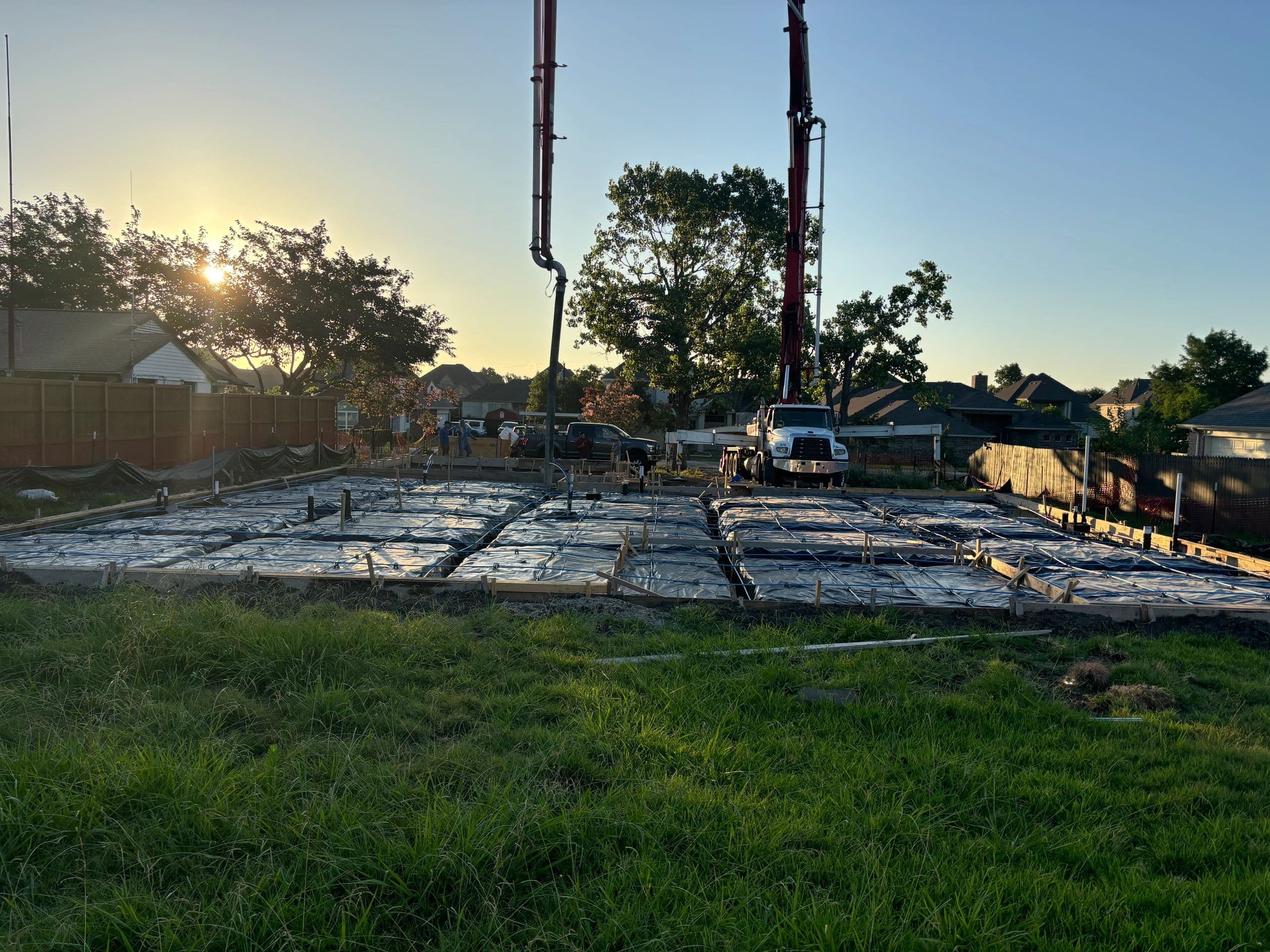 Residential foundation slab pour at sunset with pump truck