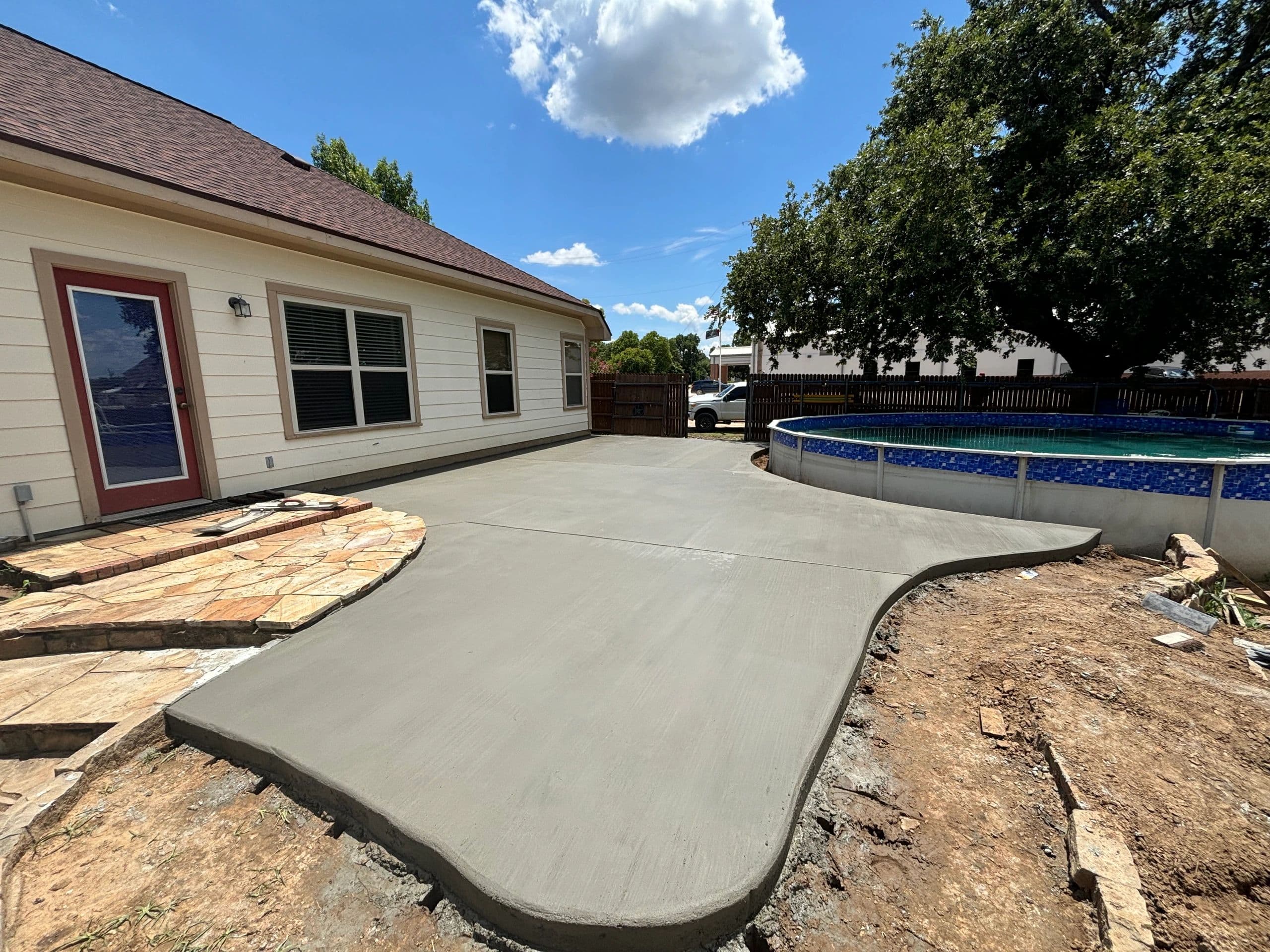 Curved concrete patio slab beside above-ground pool